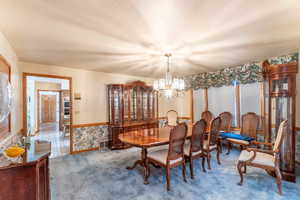 Dining room with an inviting chandelier, a textured ceiling, and carpet floors