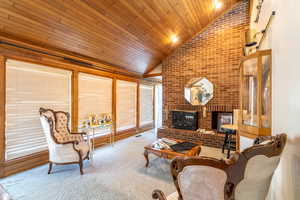 Living room featuring carpet, wood ceiling, vaulted ceiling, and a brick fireplace