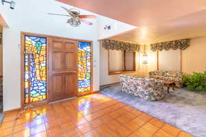 Entryway featuring a textured ceiling, ceiling fan, and light tile patterned floors