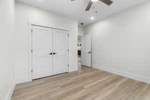 Main level flex room/bedroom featuring ceiling fan, a closet, and light hardwood / wood-style flooring
