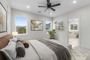 Primary bedroom featuring ensuite bath, ceiling fan, and light carpet