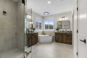 Primary bedroom ensuite bath with tile patterned flooring, dual vanities, and full tile shower with separate bathtub