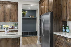 Kitchen featuring backsplash, stainless steel fridge, light hardwood / wood-style flooring, and light stone counters