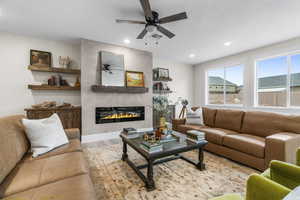 Living room with a large fireplace, ceiling fan, hardwood / wood-style floors, and a textured ceiling