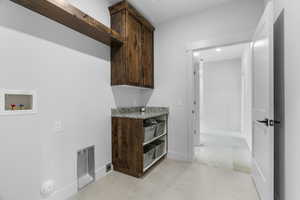 Laundry room with cabinets, washer hookup, light tile patterned floors, and electric dryer hookup. Private entry to primary ensuite closet
