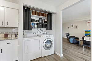 Laundry area featuring light hardwood / wood-style floors, a textured ceiling, and washing machine and clothes dryer