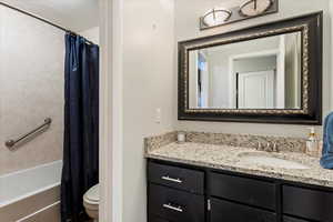 Full bathroom featuring vanity, shower / bath combo with shower curtain, and toilet