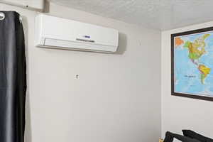 Interior details featuring a textured ceiling and a wall mounted air conditioner