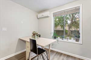 Dining space with a textured ceiling, a wall mounted AC, and dark hardwood / wood-style flooring