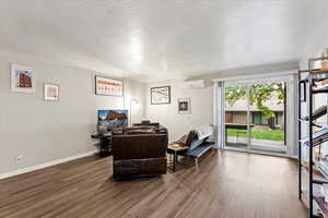 Interior space featuring hardwood / wood-style floors, a textured ceiling, and a wall mounted air conditioner