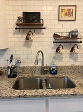 Kitchen featuring backsplash, sink, and light stone counters