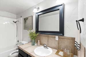 Full bathroom: bath tub / shower combination, tasteful backsplash, vanity, and toilet