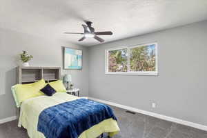 Bedroom with ceiling fan, a textured ceiling, and carpet