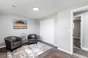 Sitting room featuring a textured ceiling and carpet