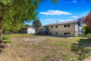 Back of property with cooling unit, a deck, a lawn, and a patio