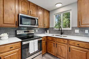 Kitchen featuring light hardwood / wood-style floors, appliances with stainless steel finishes, sink, and decorative backsplash