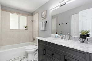 Full bathroom with vanity, tiled shower / bath combo, and toilet