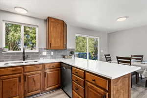 Kitchen featuring dishwasher, sink, kitchen peninsula, light hardwood / wood-style flooring, and backsplash