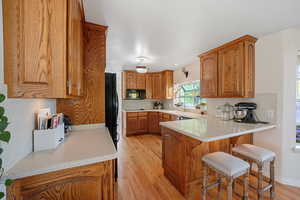 Kitchen featuring light hardwood / wood-style floors, a breakfast bar, sink, kitchen peninsula, and black appliances