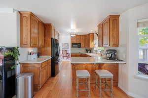 Kitchen with sink, light hardwood / wood-style floors, kitchen peninsula, , and a kitchen breakfast bar