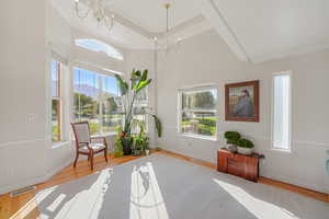 Sitting room featuring light wood-type flooring, crown molding, a chandelier, and a healthy amount of sunlight