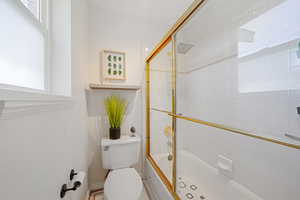 Bathroom with combined bath / shower with glass door and toilet