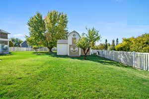 View of yard featuring a mini barn for storage and mature trees.