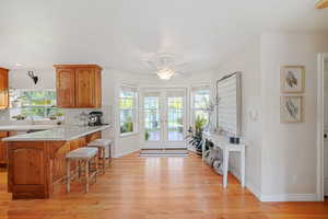 Kitchen featuring ceiling fan, a breakfast bar area, light wood-type flooring, and kitchen peninsula