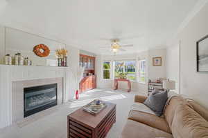 Carpeted living room with a fireplace, ornamental molding, a textured ceiling, and ceiling fan