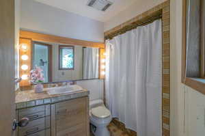 Bathroom featuring walk in shower, tile patterned floors, vanity, and toilet