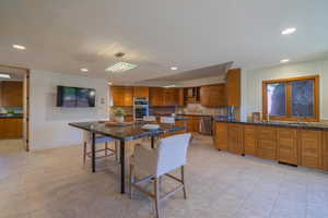 Kitchen featuring sink, a kitchen island, appliances with stainless steel finishes, a kitchen breakfast bar, and decorative backsplash