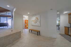 Hallway featuring light tile patterned flooring and an inviting chandelier