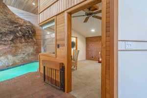 Hall with carpet flooring and vaulted ceiling