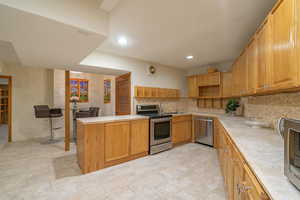 Kitchen featuring kitchen peninsula, decorative backsplash, sink, and stainless steel appliances