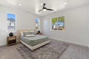 Carpeted bedroom featuring multiple windows and ceiling fan