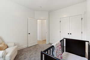 Bedroom with a crib, a closet, and light carpet