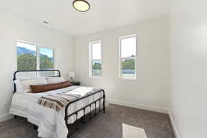 Bedroom featuring dark colored carpet and multiple windows