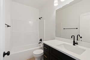 Full bathroom featuring vanity, washtub / shower combination, and toilet