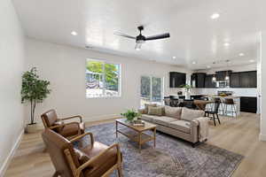 Living room featuring ceiling fan, light hardwood / wood-style floors, and a textured ceiling