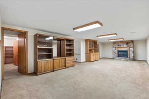 Unfurnished downstairs living room featuring a fireplace and light carpet