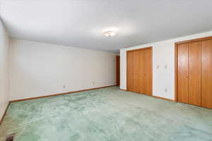 Unfurnished bedroom with multiple closets and light colored carpet