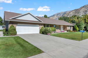 Ranch-style house featuring a garage, a front lawn, and a mountain view