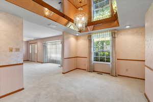 Carpeted spare room with an inviting chandelier