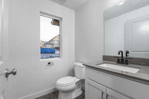 Bathroom with hardwood / wood-style flooring, a healthy amount of sunlight, toilet, and vanity