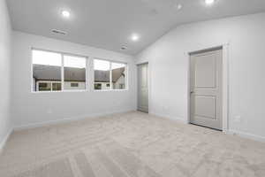 Empty room with lofted ceiling and light colored carpet