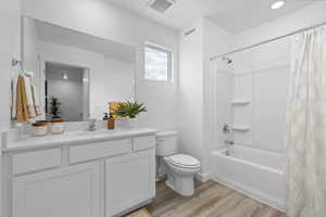 Full bathroom with shower / bath combination with curtain, vanity, hardwood / wood-style floors, and toilet