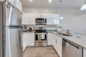 Kitchen featuring decorative light fixtures, appliances with stainless steel finishes, sink, and white cabinetry