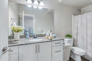 Bathroom with wood-type flooring, a textured ceiling, vanity, and toilet