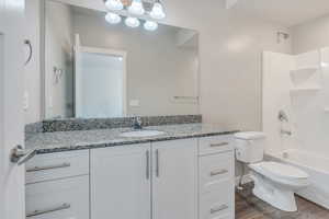 Full bathroom featuring shower / washtub combination, hardwood / wood-style flooring, vanity, and toilet