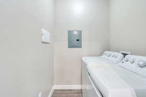 Laundry area with wood-type flooring, separate washer and dryer, and electric panel